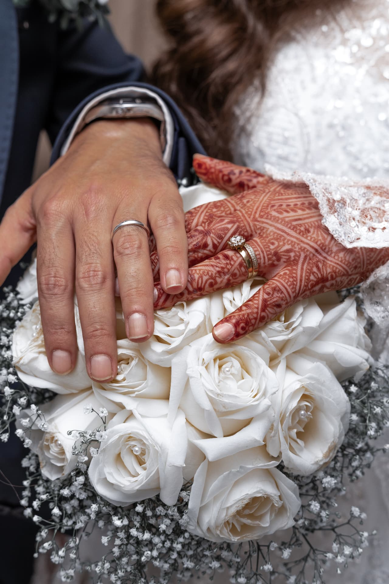 A couple's wedding rings resting on a white rose bouquet