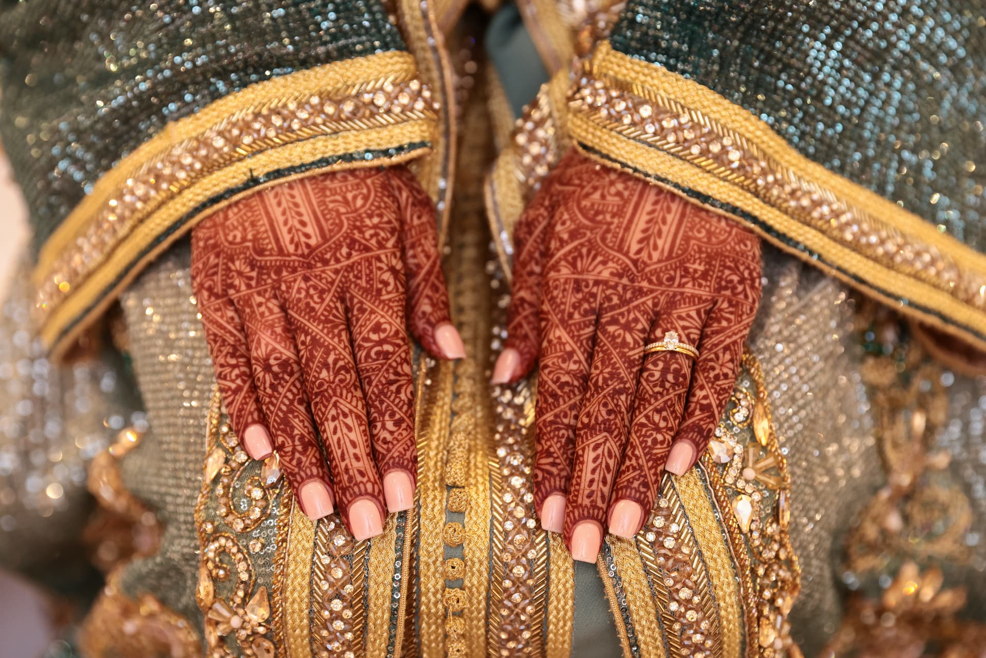 Henna-adorned hands against ornate gold embroidery