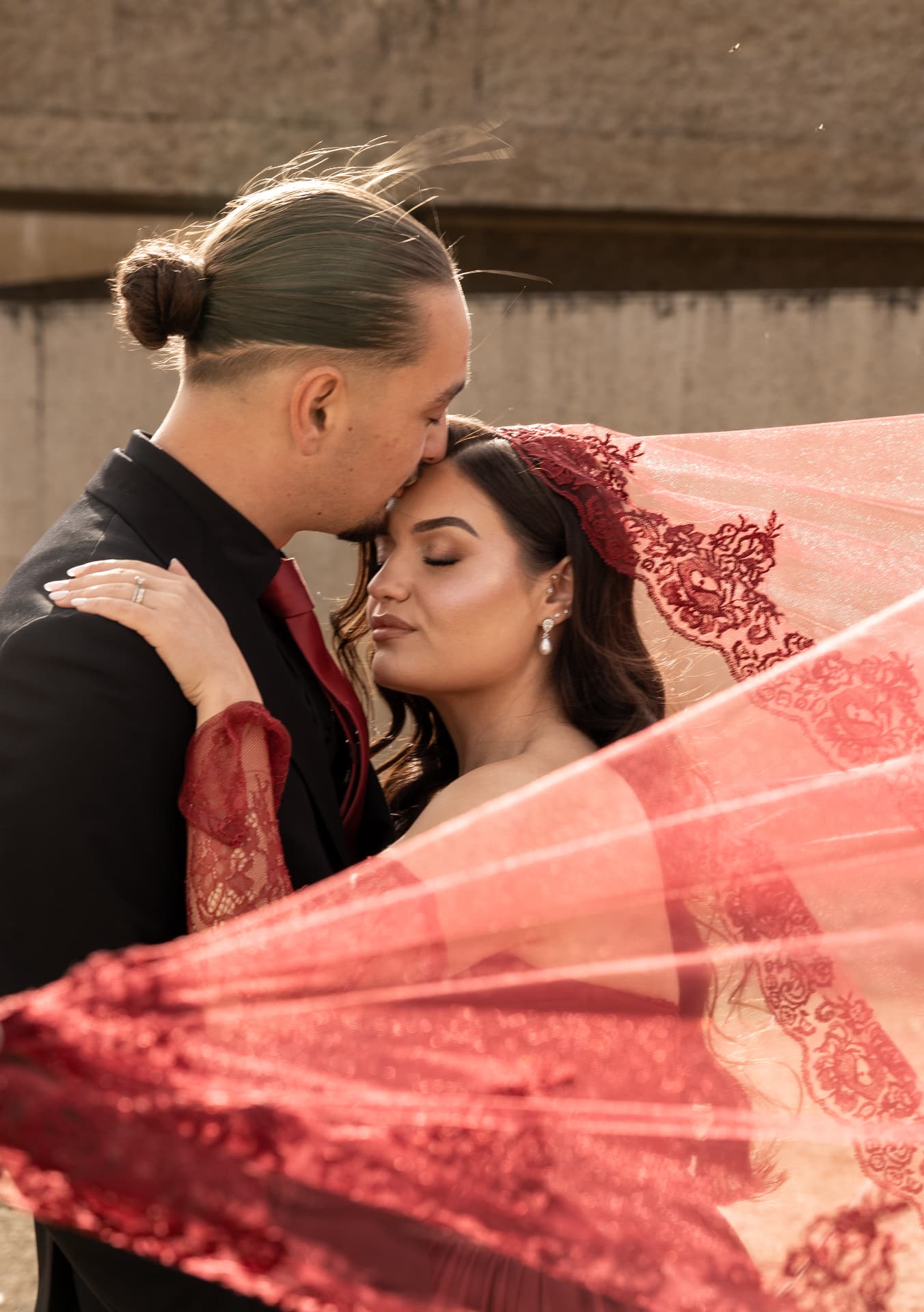 A tender close-up framed by sunlit red lace