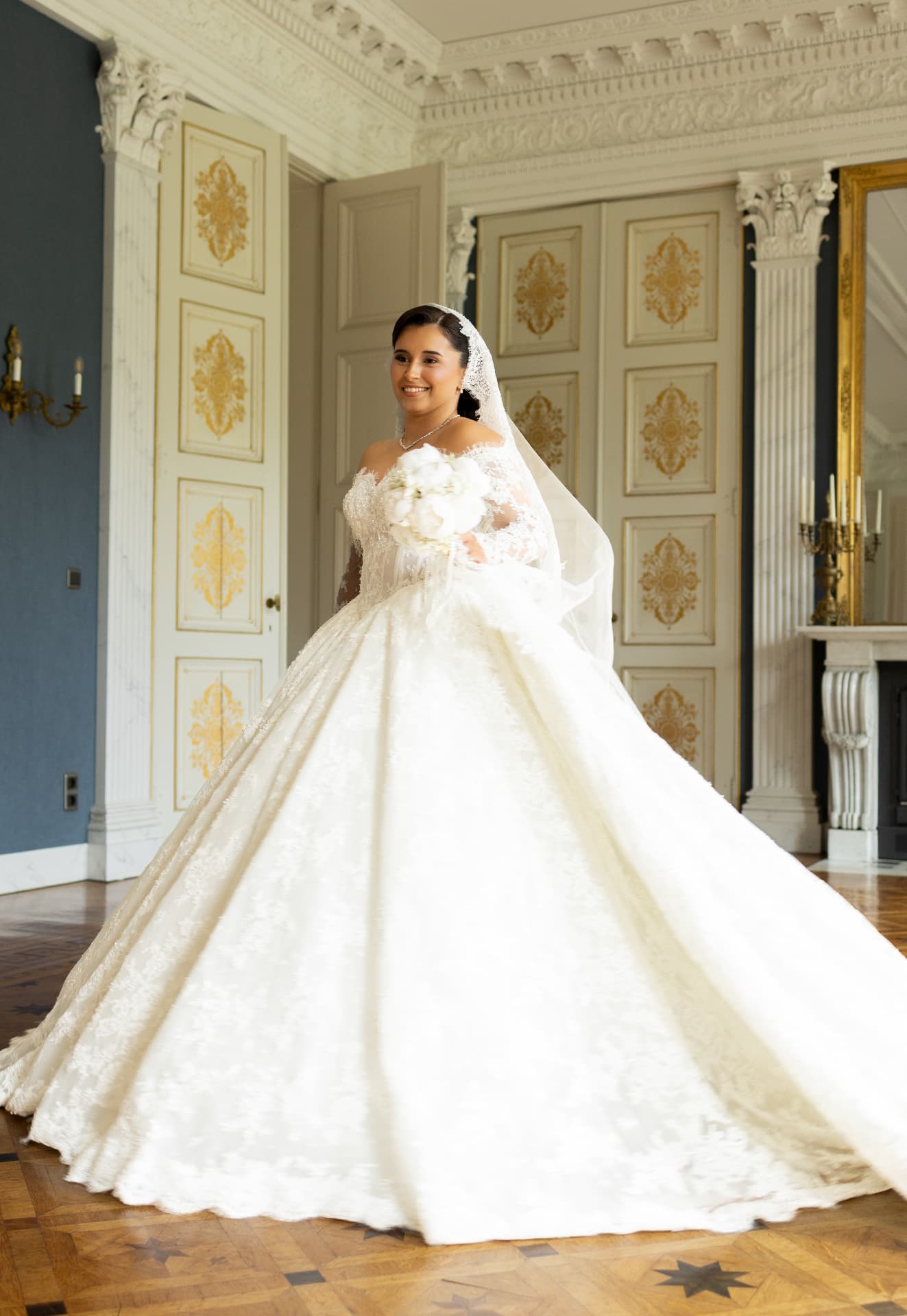 A bride in a lace wedding gown in a sunlit decorative room