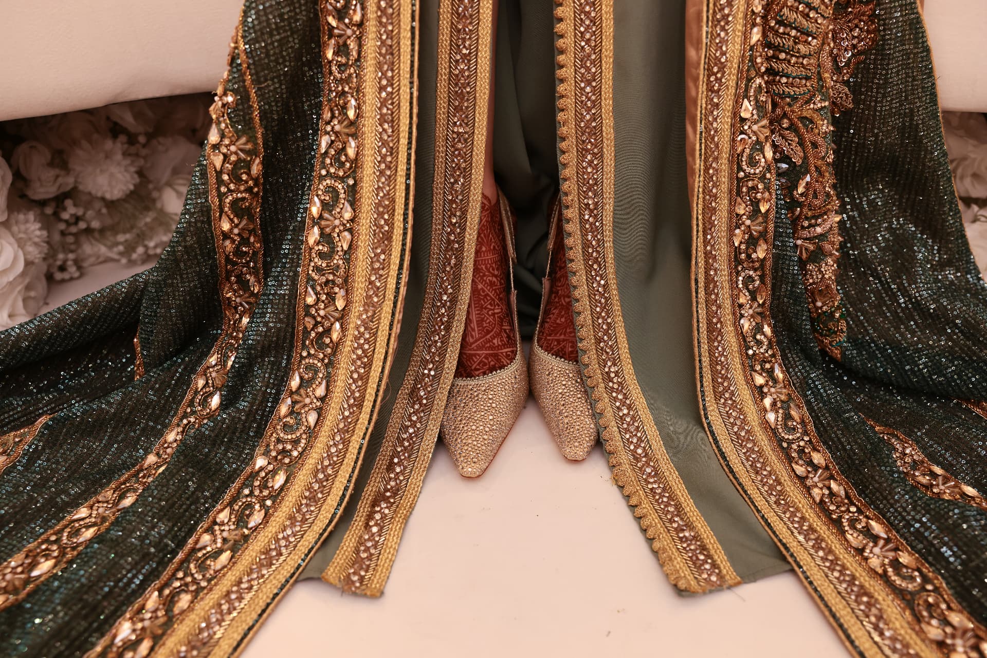 Gold embroidery and slippers beneath a traditional ceremonial gown