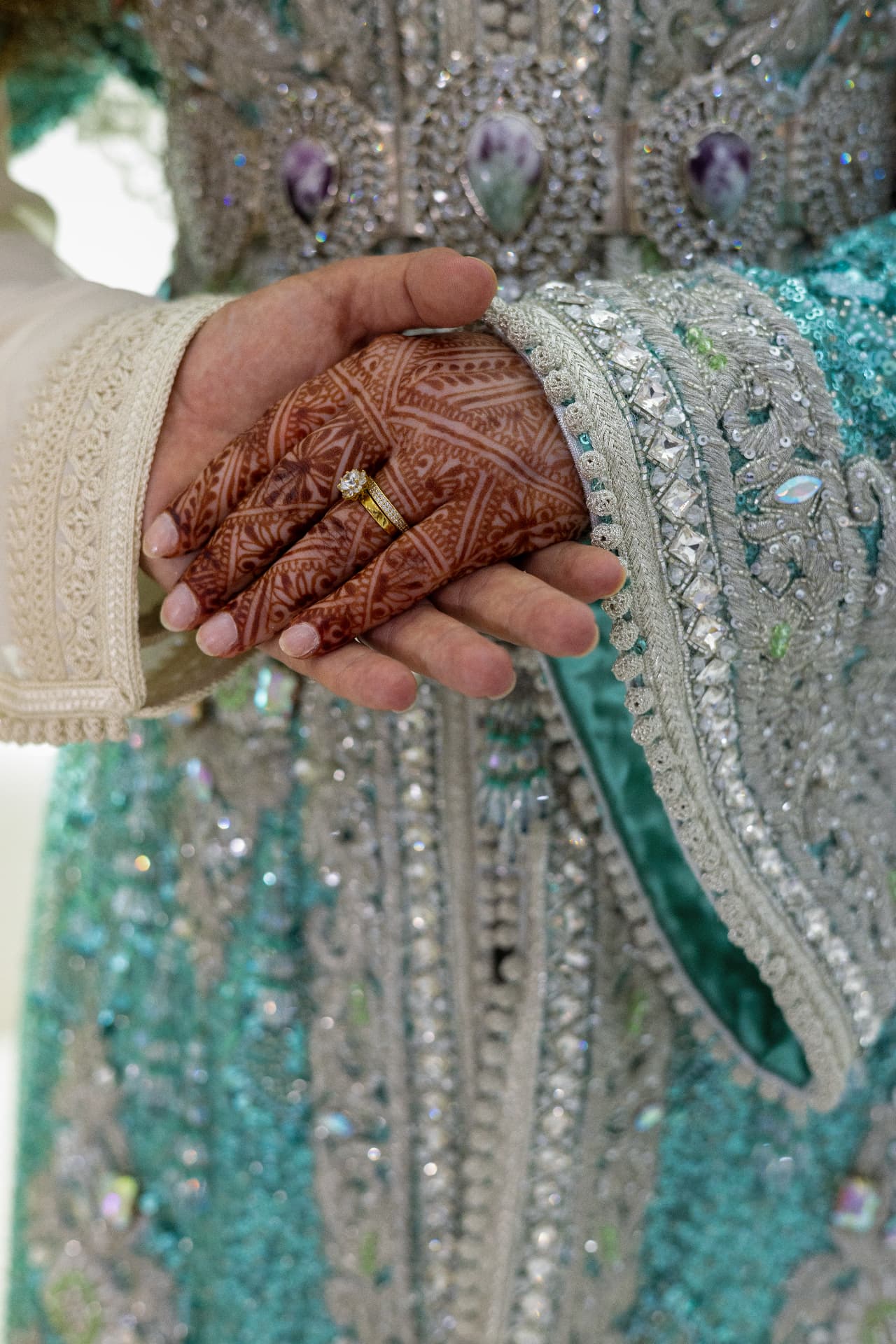 Joined hands against turquoise and silver ceremonial embroidery