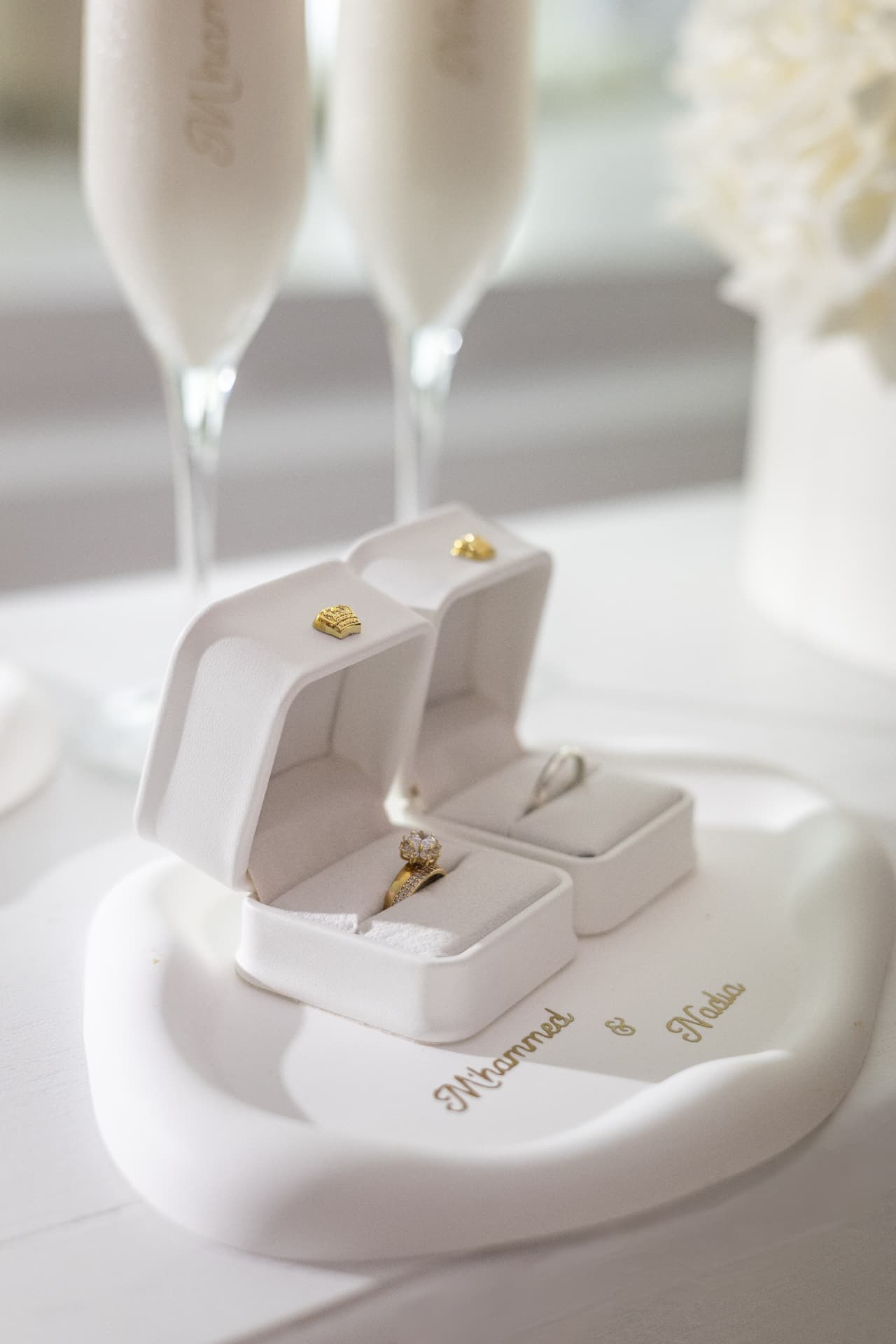 White wedding ring boxes beside two personalised glasses