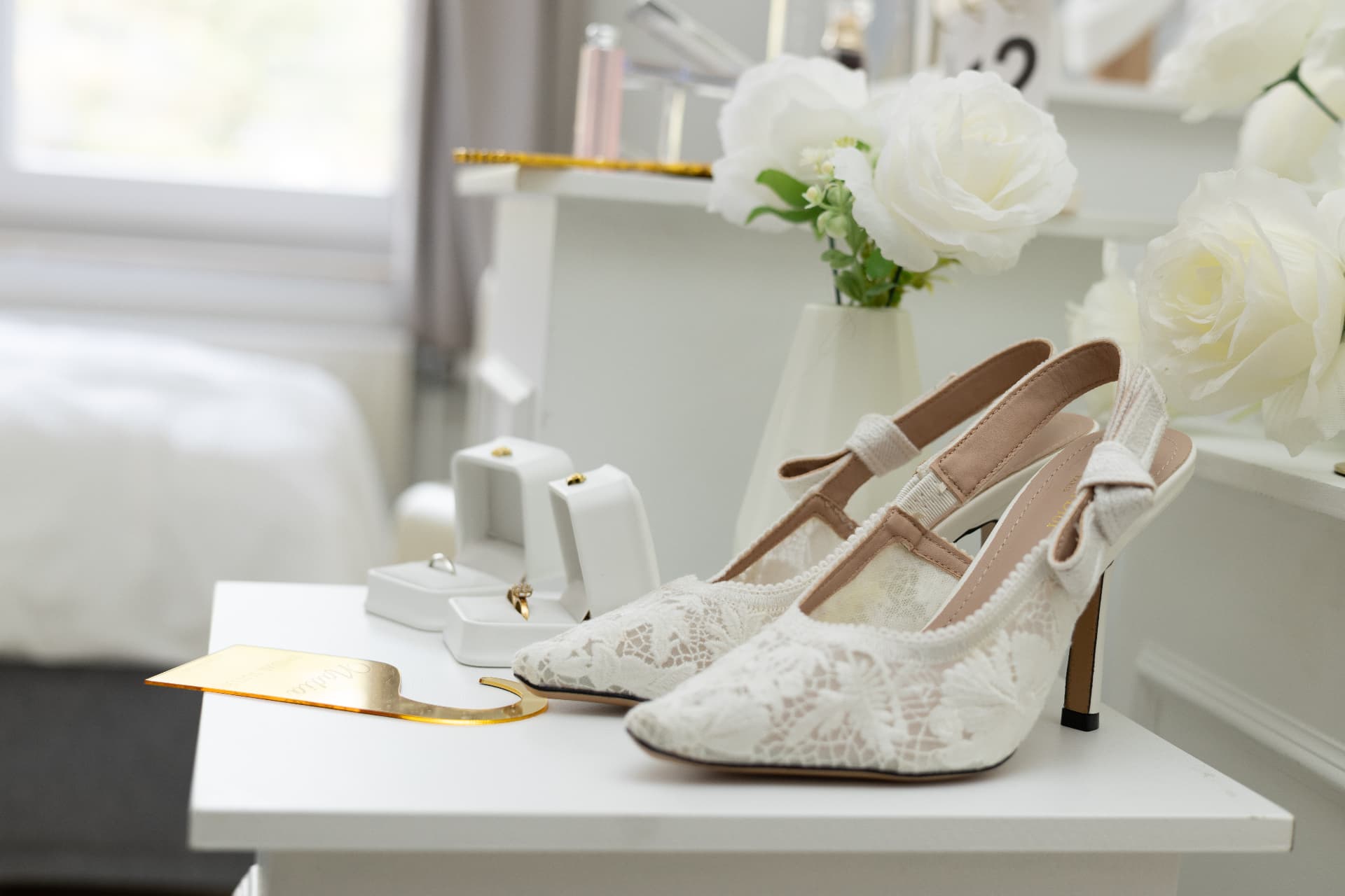 Lace bridal shoes beside white orchids and jewellery