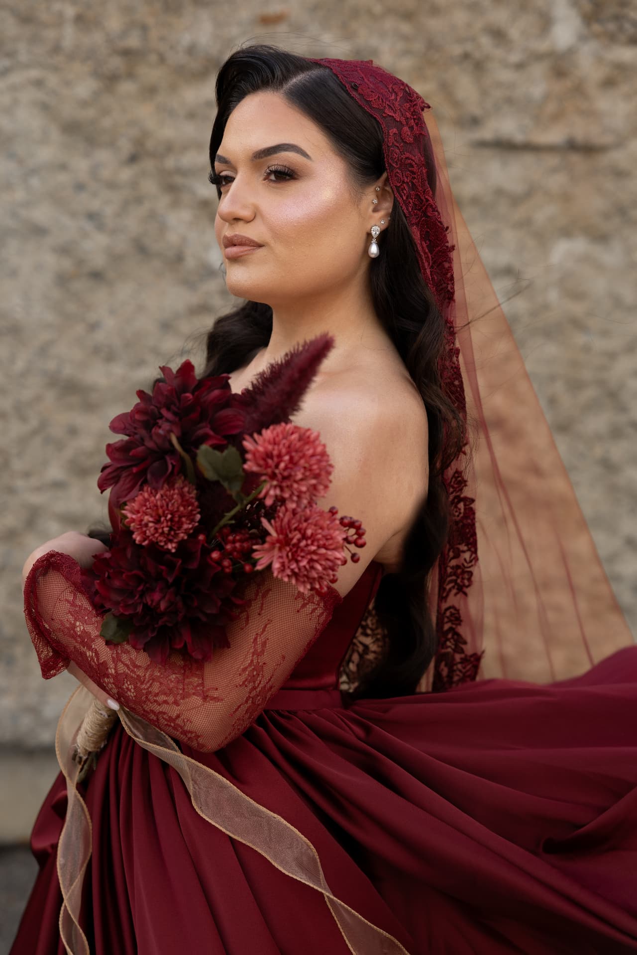A bridal portrait with a burgundy gown and matching floral bouquet