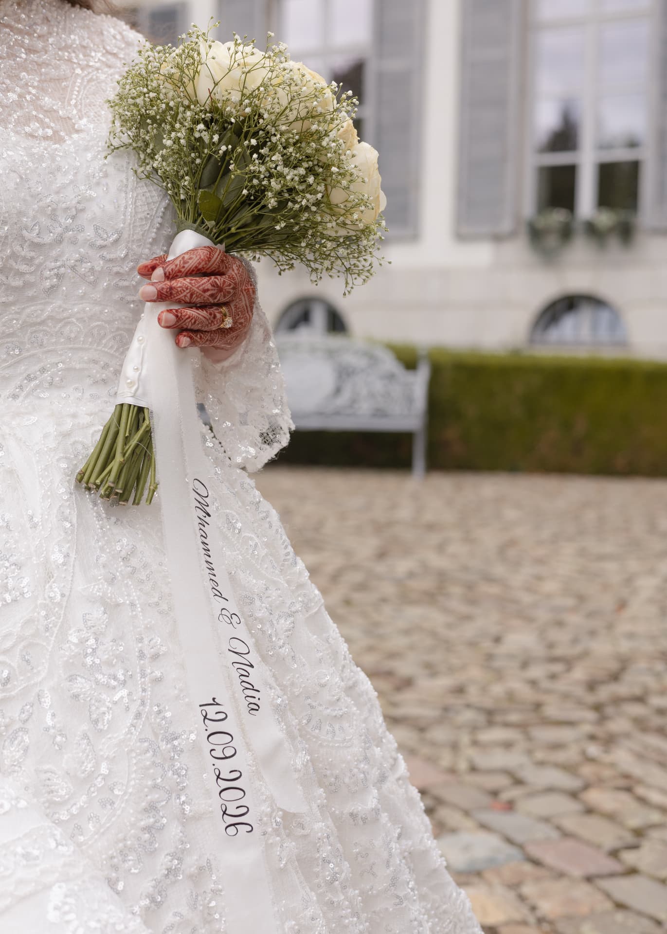 A lace bridal gown and gypsophila bouquet with a personalised ribbon