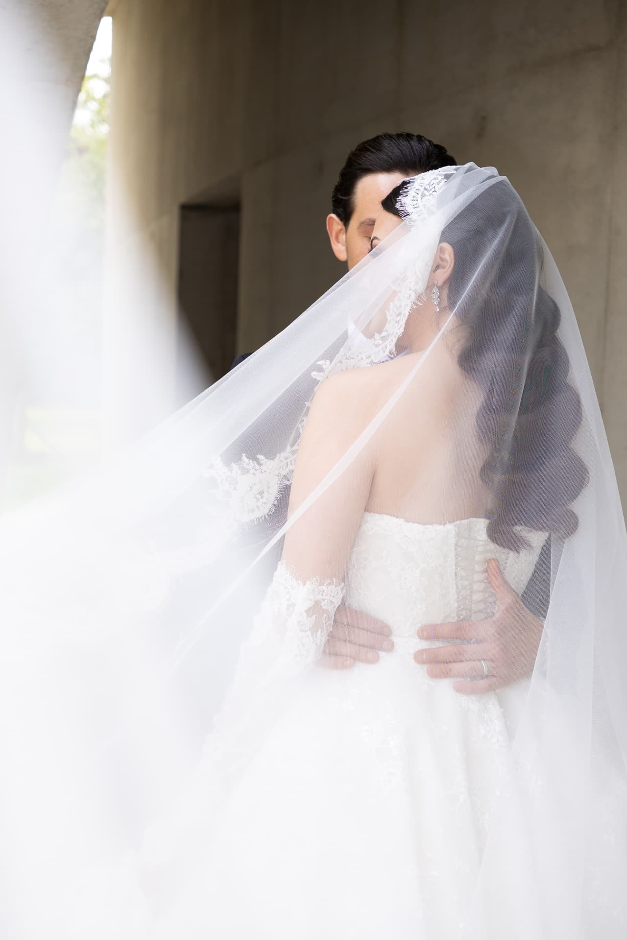A couple embracing beneath a translucent bridal veil