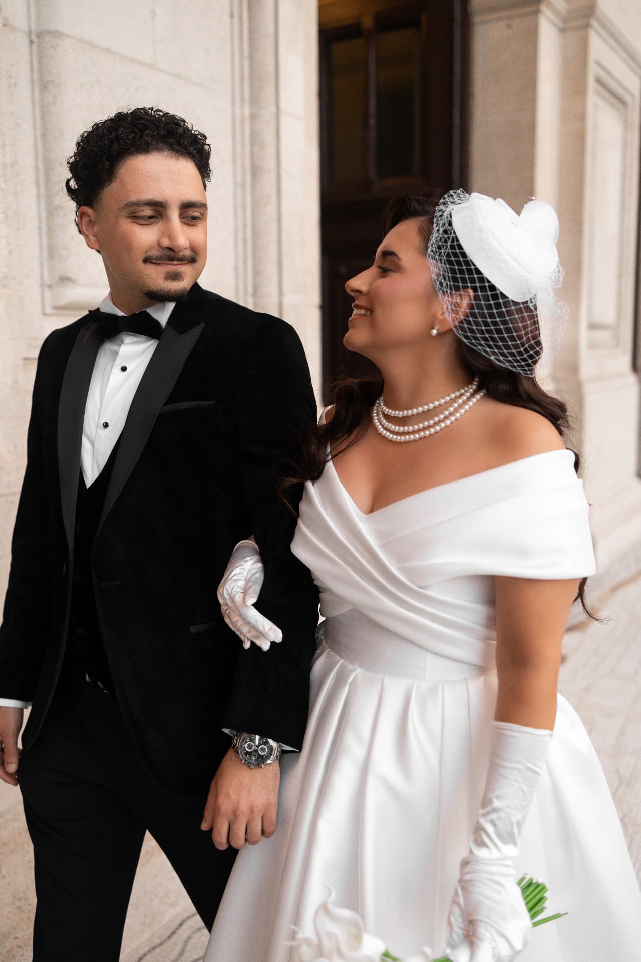 Newlyweds exchanging a smile outside a stone building