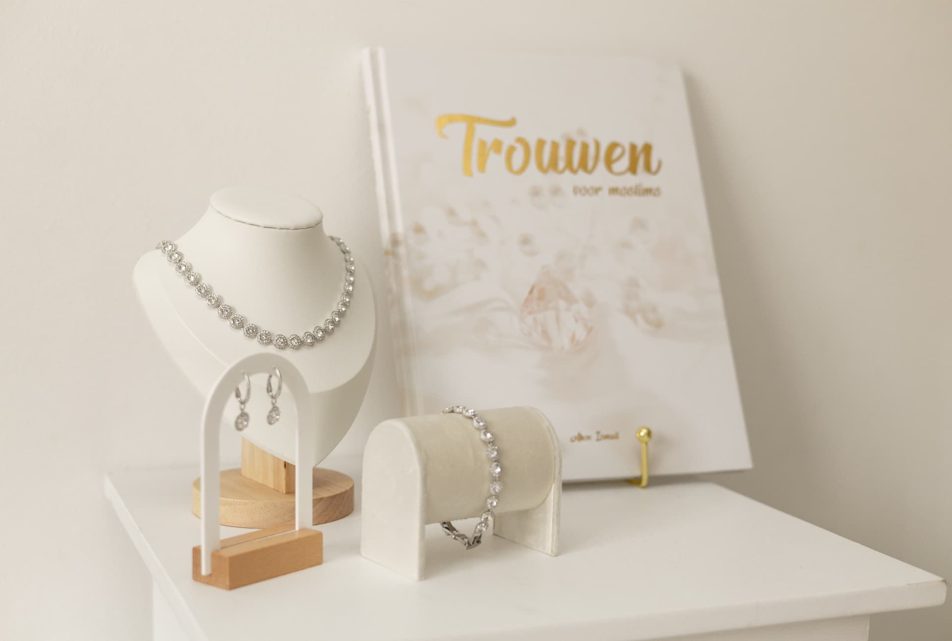Bridal jewellery and a wedding book arranged on a white shelf