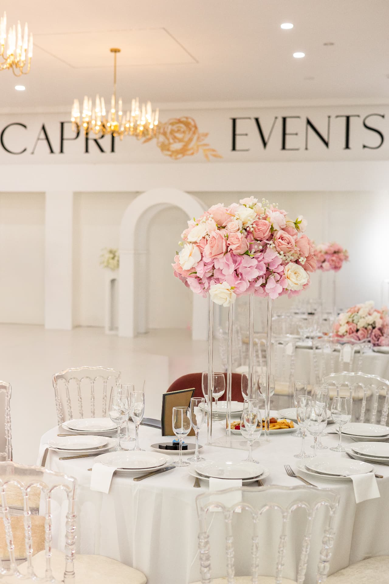 An elegant wedding reception table with pink flowers and chandeliers