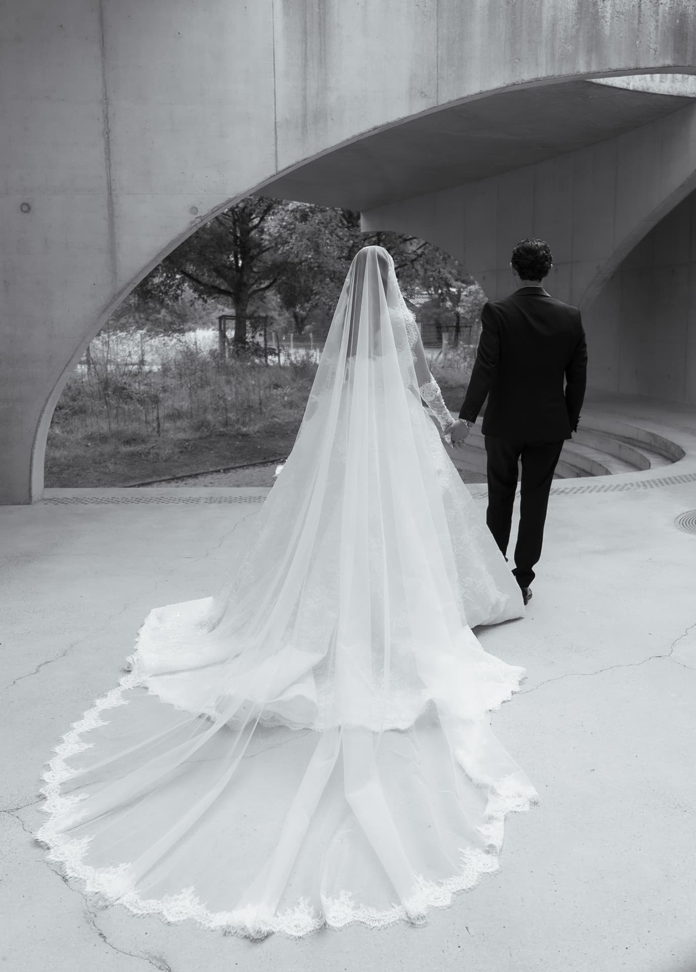 Black-and-white photograph of newlyweds walking hand in hand