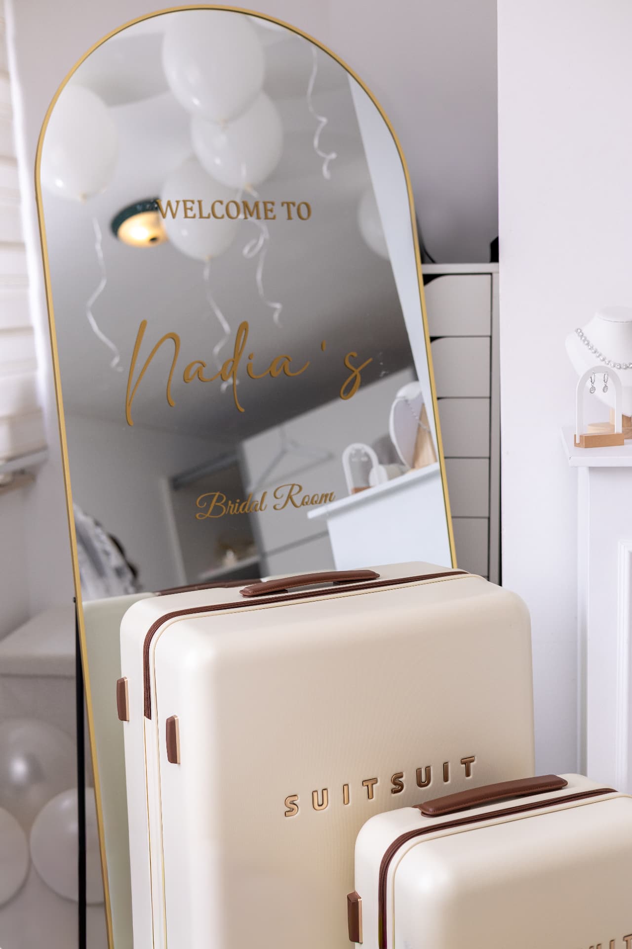 A gold-framed wedding welcome mirror with cream suitcases