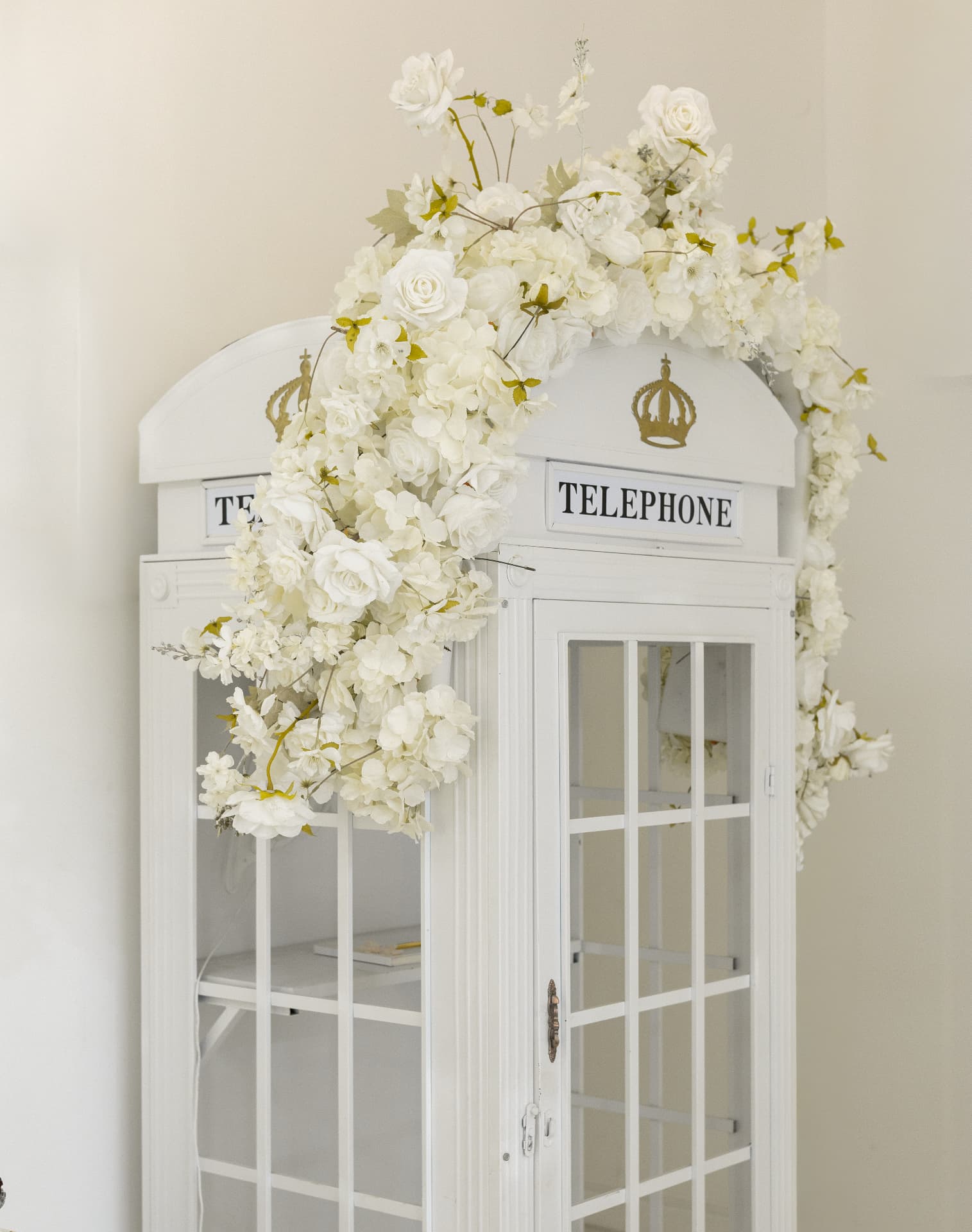 A white telephone booth decorated with cascading white flowers