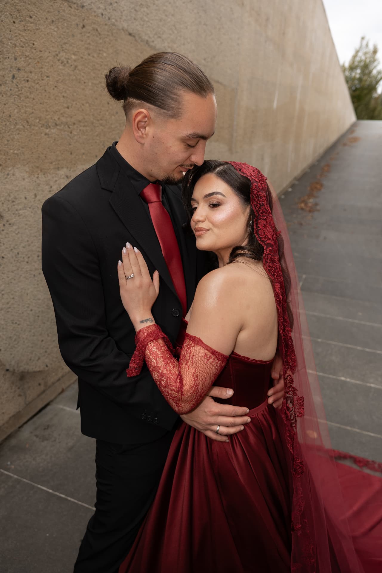 A couple embracing beside a curved concrete wall