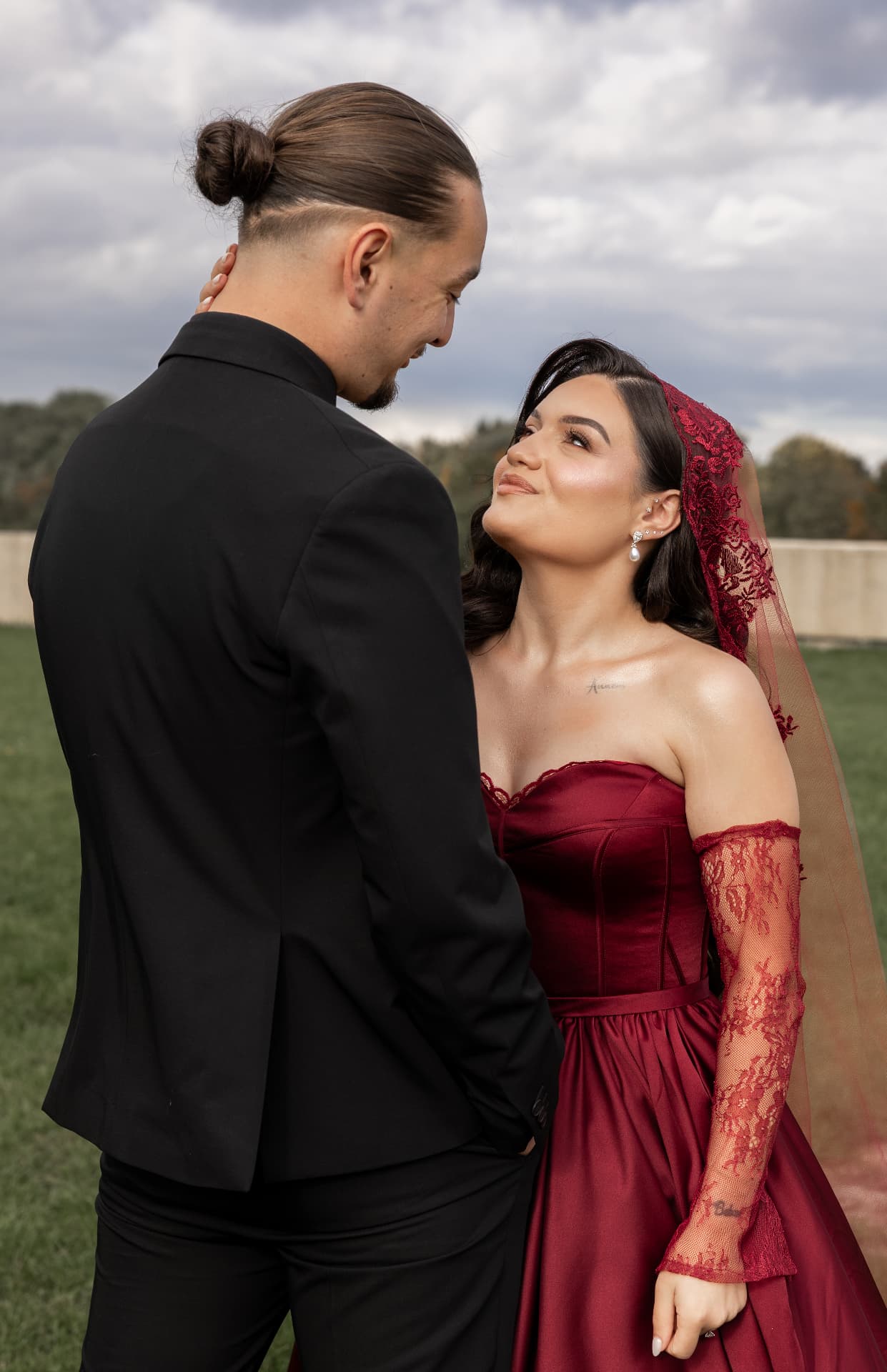 A couple exchanging a smile beneath a cloudy sky