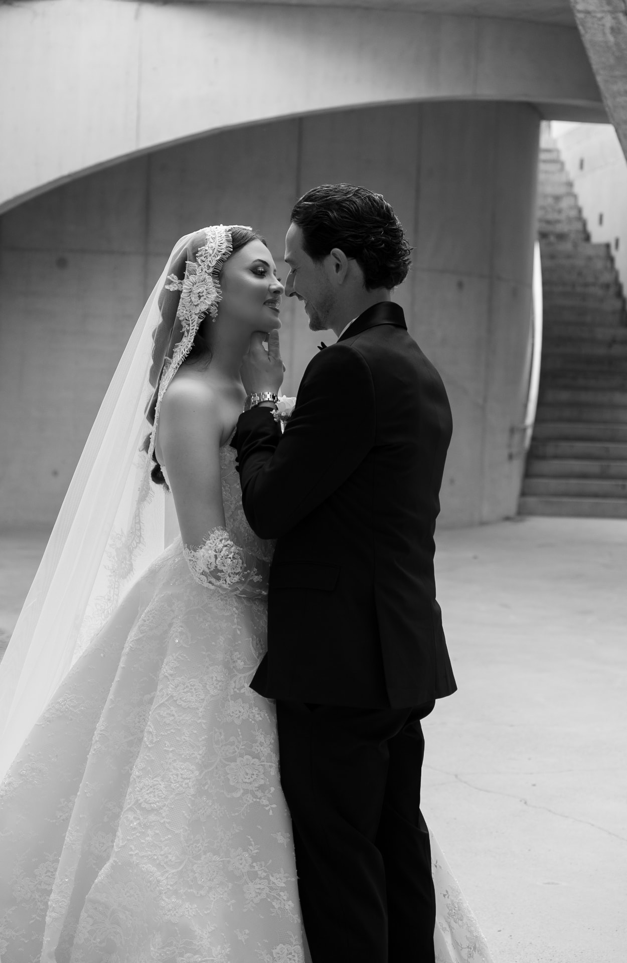 Black-and-white portrait of a couple beneath a concrete archway