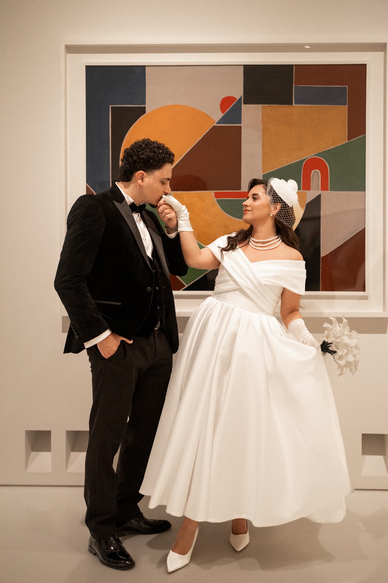 A playful wedding portrait beside a colourful abstract painting